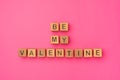 Wooden cubes with the phrase Be My Valentine on an empty colorful pink background. Words of love are made of letters Royalty Free Stock Photo