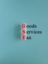 Wooden cubes with red words Goods and Services Tax on a blue background. State financial policy to regulate tax collection rules