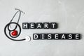 Wooden cubes with text Heart Disease and stethoscope on grey background Royalty Free Stock Photo