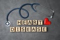 Wooden cubes with text Heart Disease and stethoscope on grey background