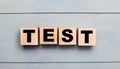 Wooden cubes with the text TEST on a light blue wooden background