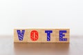 Wooden cubes with vote written against white background