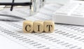 Wooden cubes with the word CIT on a financial background with chart, calculator, pen and glasses, business concept