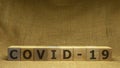 Wooden cubes with word COVID-19 on sackloth background. Pandemia and Covid-19 concept