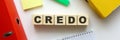 Wooden cubes with word CREDO on the office desk. Folder and other office supplies