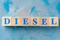 Wooden cubes with word DIESEL on blue table.