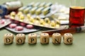 Wooden cubes with word Doping and drugs on green background, closeup