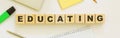 Wooden cubes with word EDUCATING on the office desk