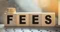 Wooden cubes with word Fees and coins on the wooden cubes. Concept of taxation, raising taxes and fees, increase and tax increases Royalty Free Stock Photo