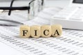 wooden cubes with the word FICA on a financial background with chart, calculator, pen and glasses, business concept Royalty Free Stock Photo