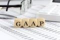 Wooden cubes with the word GAAP on a financial background with chart, calculator, pen and glasses, business concept Royalty Free Stock Photo