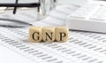 wooden cubes with the word GNP on a financial background with chart, calculator, pen and glasses, business concept Royalty Free Stock Photo