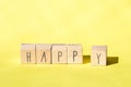 Wooden cubes with the word Happy on Bright Yellow background, Cheerful concept Royalty Free Stock Photo