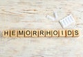 Wooden cubes with word HEMORRHOID and suppositories on white table