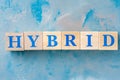 Wooden cubes with word HYBRID on blue table. Royalty Free Stock Photo