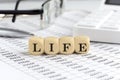 wooden cubes with the word LIFE on a financial background with chart, calculator, pen and glasses, business concept Royalty Free Stock Photo