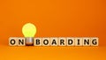 Wooden cubes with word `onboarding`. Yellow light bulb. Beautiful orange background. Business concept. Copy space