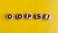 The wooden cubes with the word oops on a yellow background. Apologies for any mistake or error