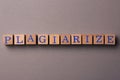 Wooden cubes with word Plagiarism on grey background, flat lay