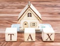 Wooden cubes with word tax, money and model of house on the wooden background. Property tax concept Royalty Free Stock Photo