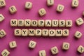 Wooden cubes with words Menopause Symptoms on pink background, flat lay