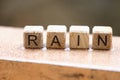 Wooden cubes with words rain lying on wet windowsill closeup