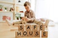 Wooden cubes with words SAFE HOUSE in hands of little boy