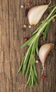 wooden culinary background with garlic, rosemary, bay leaves, pepper and some cloves pictured on it Royalty Free Stock Photo