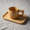 A wooden cup with a circular handle rests on a matching rectangular wooden tray. The cup and tray Royalty Free Stock Photo