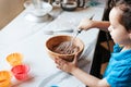 A wooden cup with a dough in the hands of a child Royalty Free Stock Photo