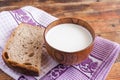 A wooden cup of milk and one bread slice are on lilac kitchen to Royalty Free Stock Photo