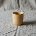 A wooden cup with a smooth, light brown finish rests on a wrinkled gray fabric surface. The cup has Royalty Free Stock Photo