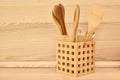 Wooden cutlery, bamboo Spatulas and spoons in wooden basket on beige kitchen countertop. Beige kitchen interior with wooden spoons