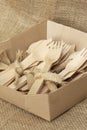Wooden cutlery, tied with hessian jute fabric, in a cardboard tray on hessian fabric. Eco friendly recycling concept