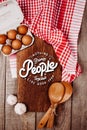 Wooden cutting board on a wooden background with garlic, ladles, eggs and a blank notebook