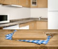 Wooden cutting board, blue checkered towel over blurred kitchen background Royalty Free Stock Photo