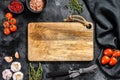 Wooden cutting board in center of Fresh raw greens, vegetables. Healthy, clean eating, vegan, dieting food concept. Black Royalty Free Stock Photo