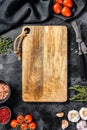 Wooden cutting board in center of Fresh raw greens, vegetables. Healthy, clean eating, vegan, dieting food concept. Black Royalty Free Stock Photo