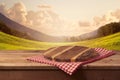 Wooden cutting board with checked tablecloth on table over landscape background