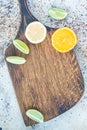 Wooden cutting board with citrus on concrete background, copy space