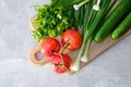 Wooden cutting board with fresh vegetables on stone concrete table. Top view tomatoes, cucumbers, onion, parsley. Fresh healthy Royalty Free Stock Photo