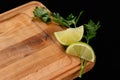 Wooden cutting board with greens and lime on a black background Royalty Free Stock Photo