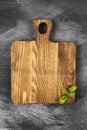 Wooden cutting board and leaves of basil on dark background. Top Royalty Free Stock Photo