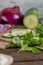 Wooden cutting board on old wooden table top with tablecloth, sliced red onion and cucumber and corn salad Royalty Free Stock Photo