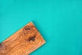 Wooden cutting board from olive tree on turquoise background. Cooking, recipe concept.