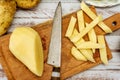 Wooden cutting board with a potato cut into a stick shape to make French fries. Half a peeled potato and a knife on a rustic table Royalty Free Stock Photo