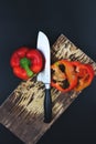 Wooden Cutting Board with Raw Vegetables pepper on Rustic Cutting Board. Sliced pepper and knife with wooden handle on Rustic