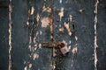 Wooden dark grey door background locked with rusty padlock. Aged entrance, close up view with details.