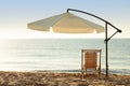 Wooden deck chair and outdoor umbrella on sandy beach. Summer vacation Royalty Free Stock Photo