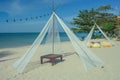 Wooden deck chair in white pavilion on sand beach with beautiful seascape view and blue sky in background. Royalty Free Stock Photo